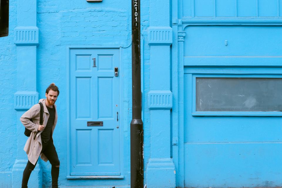 bearded man with backpack in front of a door